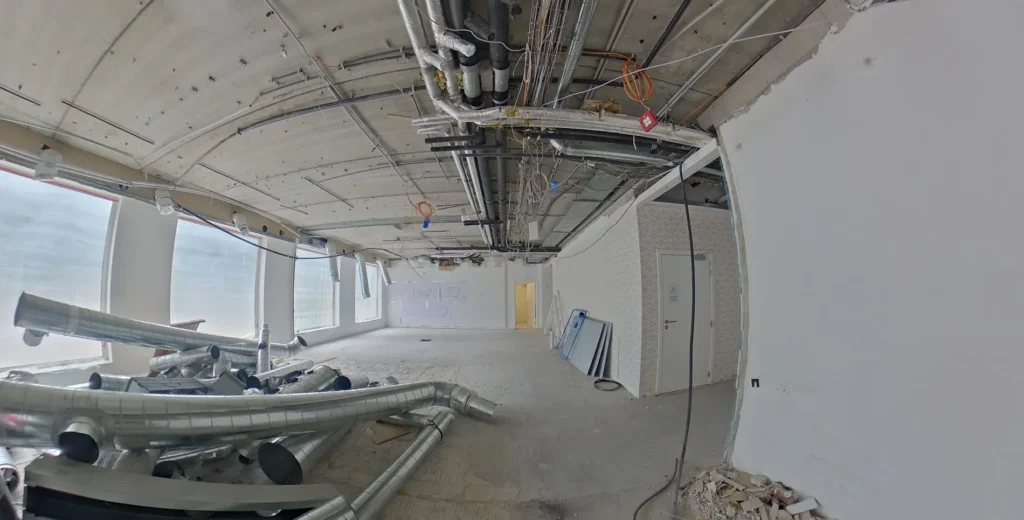 Keskeneräinen toimitilan saneeraus, näkyvissä katossa talotekniikan asennuksia ja lattialla rakennusmateriaaleja.